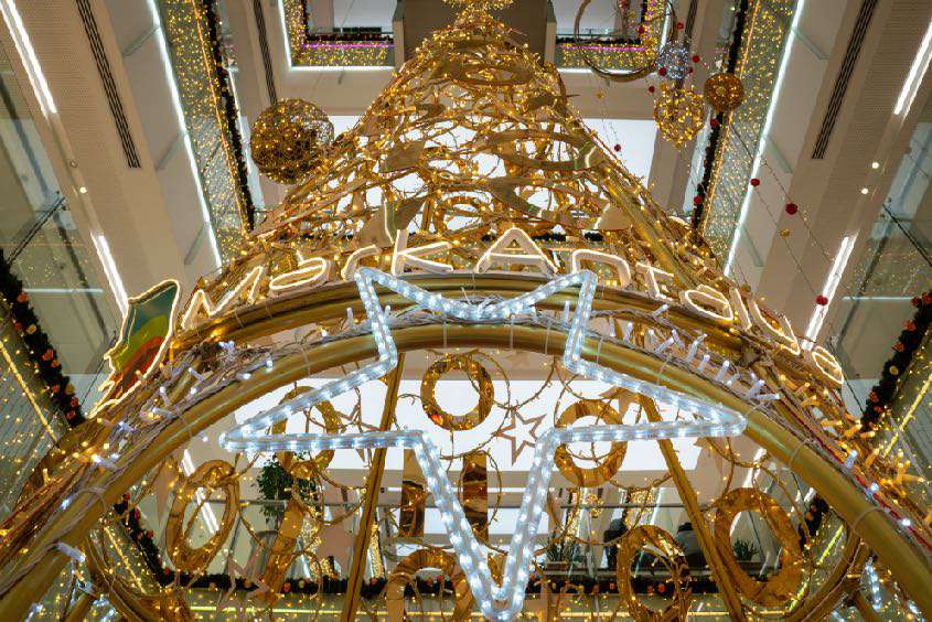Holiday Modular Display – Golden Tree Installation Large modular holiday display with gold framework and lighting inside a shopping mall atrium.