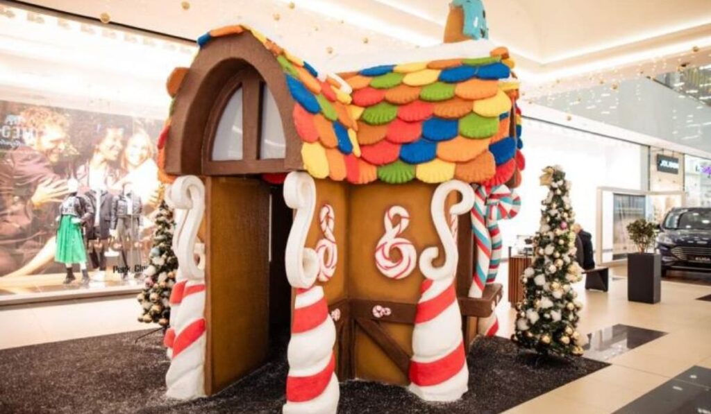 Colorful gingerbread-style holiday house fabricated by Alice Scenic Studios inside a shopping mall
